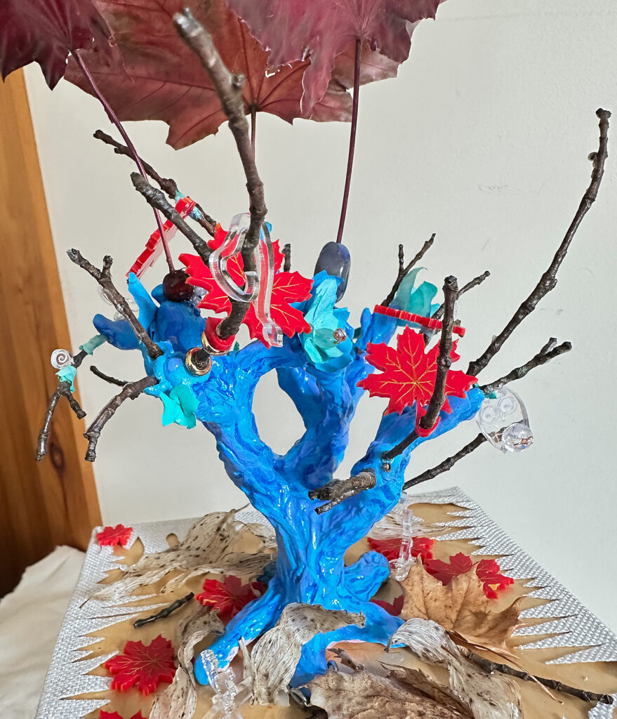 A close up view of the top of the table. We can see dried leaves, acrylic leaves, and clear acrylic animals lurking on the piece.