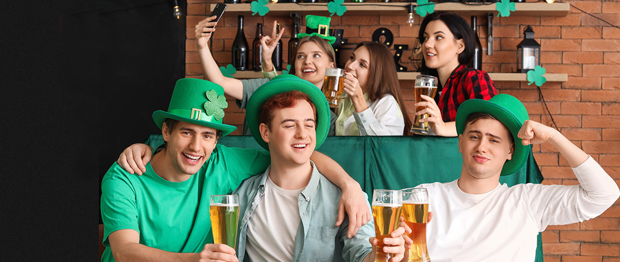 Three white men and three white women celebrate at a bar with beer and a Three white men and three white women celebrate at a bar with beer and Saint Patrick day regalia.